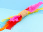 Jute rope barrel shaped rattle toy with bright turkey feathers at each end